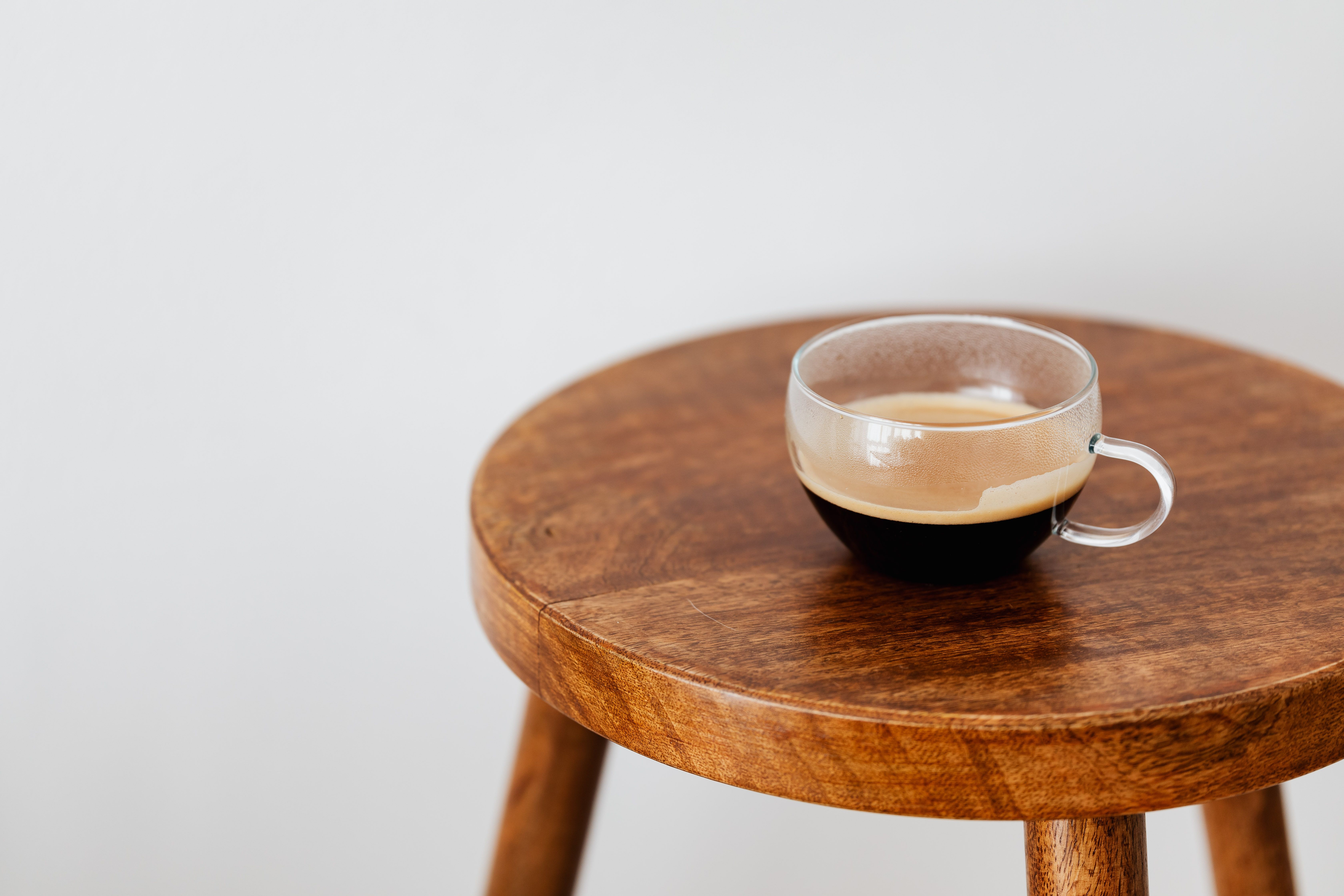 Un café dans une tasse en verre, sur une table en bois.